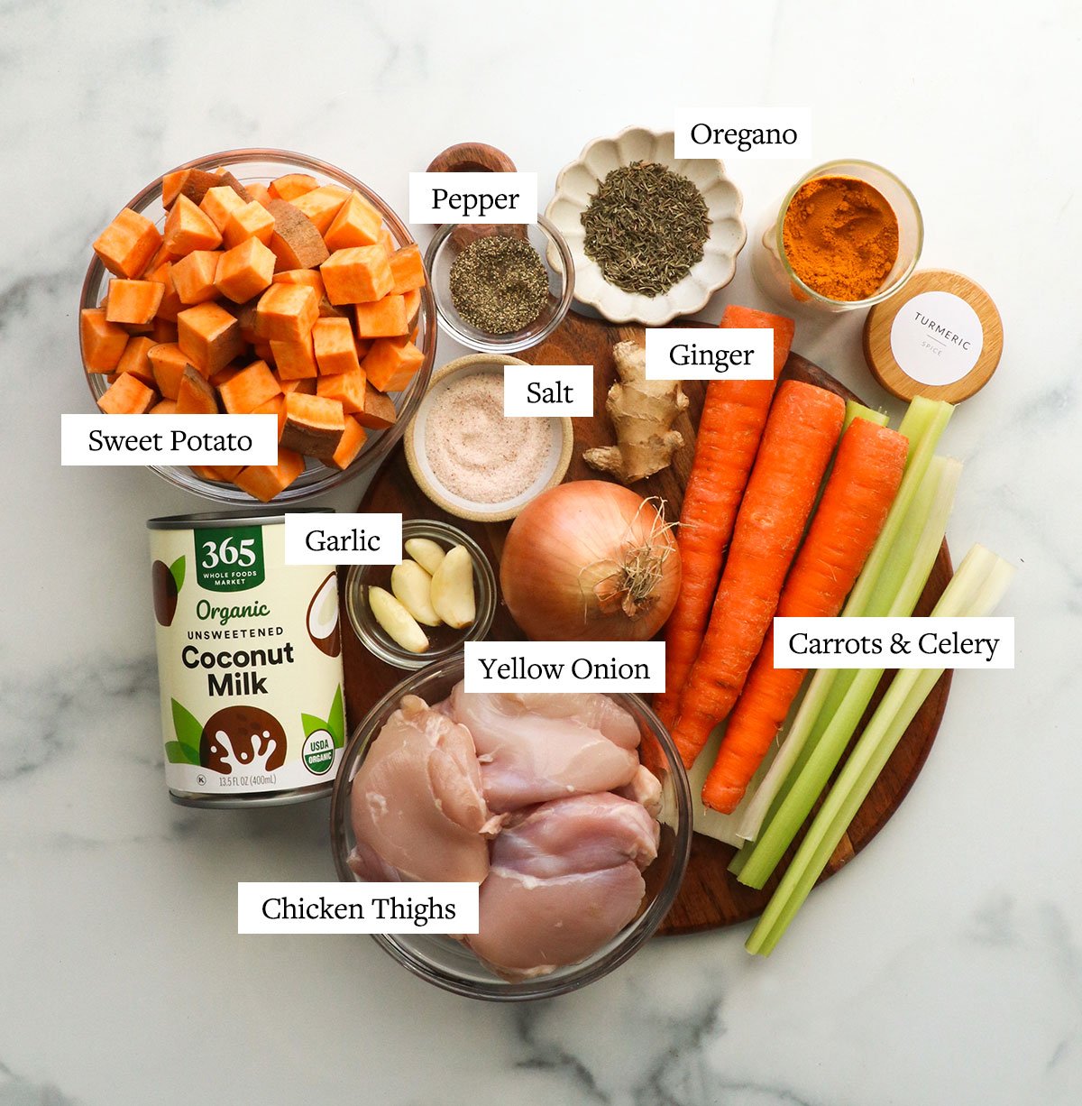 sweet potatoes, chicken thighs, carrots, celery, and spices on a cutting board.