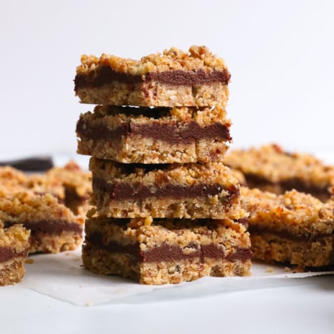 chocolate walnut bars stacked on white parchment paper.