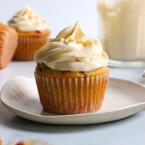 healthy cream cheese frosting piped on top of a muffin on a white plate.