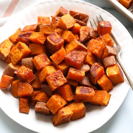 roasted sweet potato cubes served on a white plate with a fork.