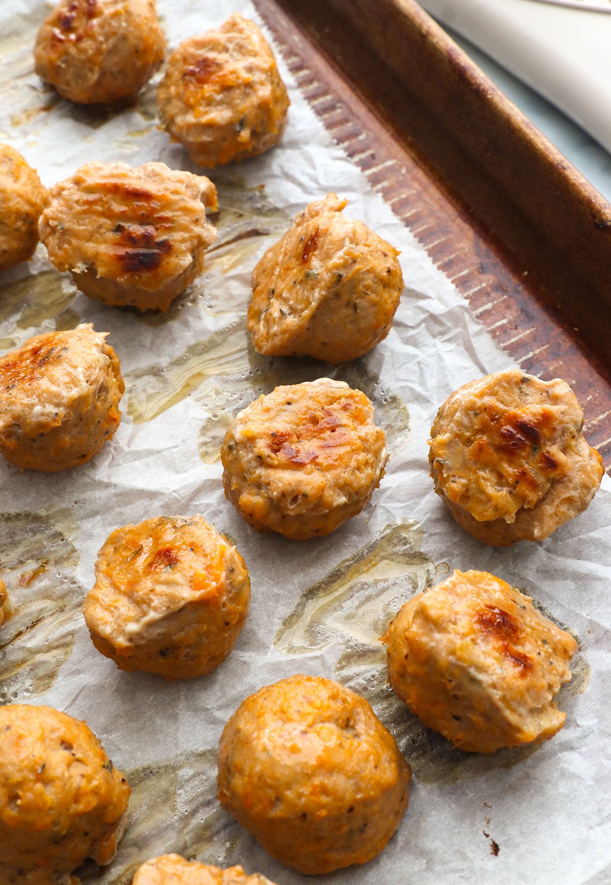 finished baked turkey meatballs on a lined pan.