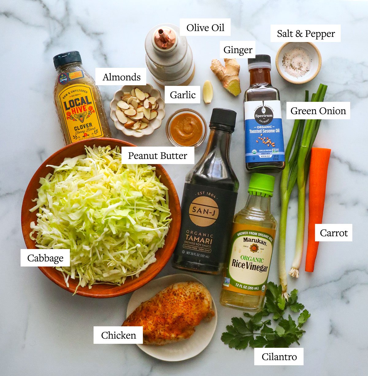 bowls of peanut butter, cabbage, almonds and more labeled on a white surface.