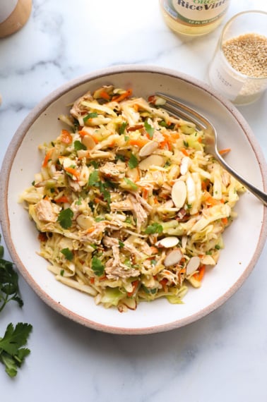 chinese chicken salad topped with cilantro in a white bowl.