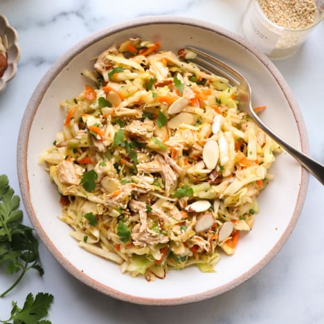 chinese chicken salad topped with cilantro in a white bowl.