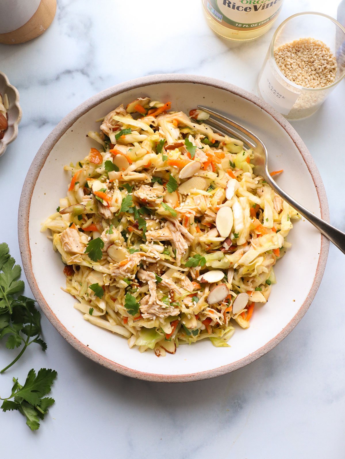 chinese chicken salad topped with cilantro in a white bowl.