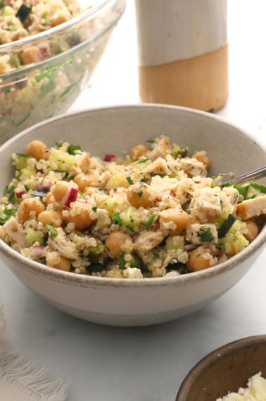 quinoa salad with chickpeas, red onion, and chicken in a bowl with fresh herbs.