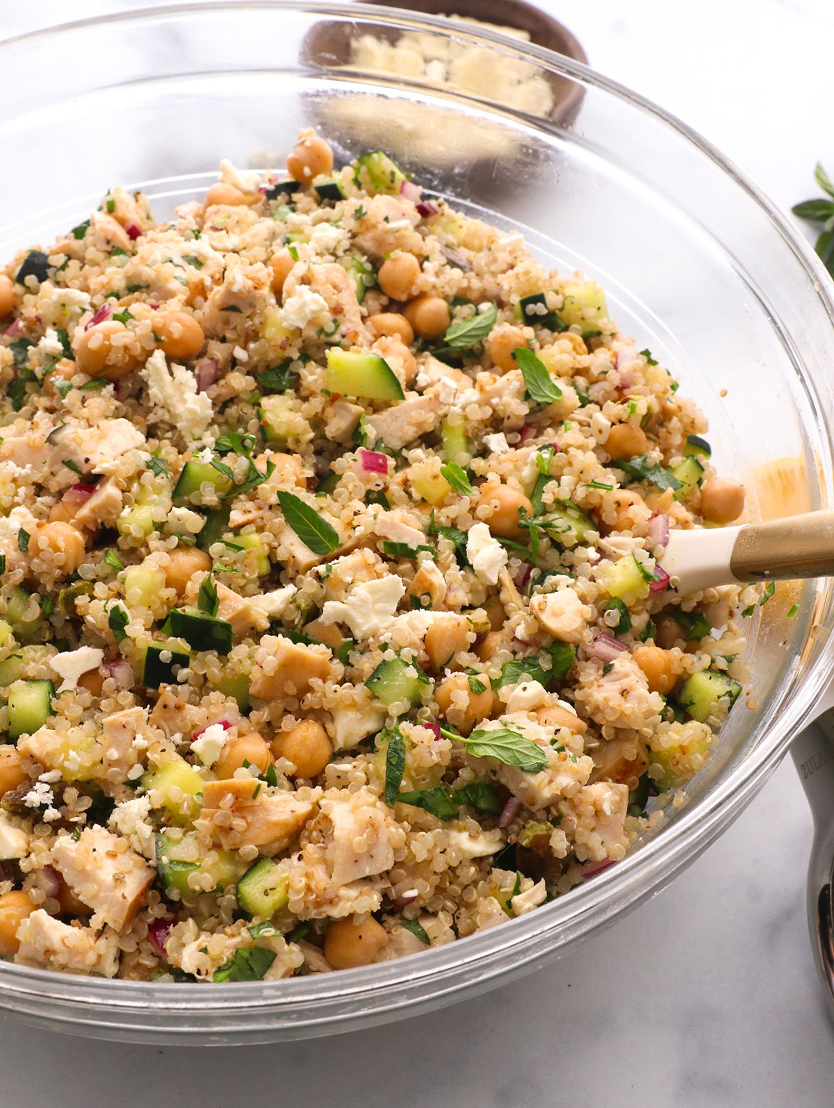 jennifer aniston salad stirred in a large glass bowl topped with fresh herbs.