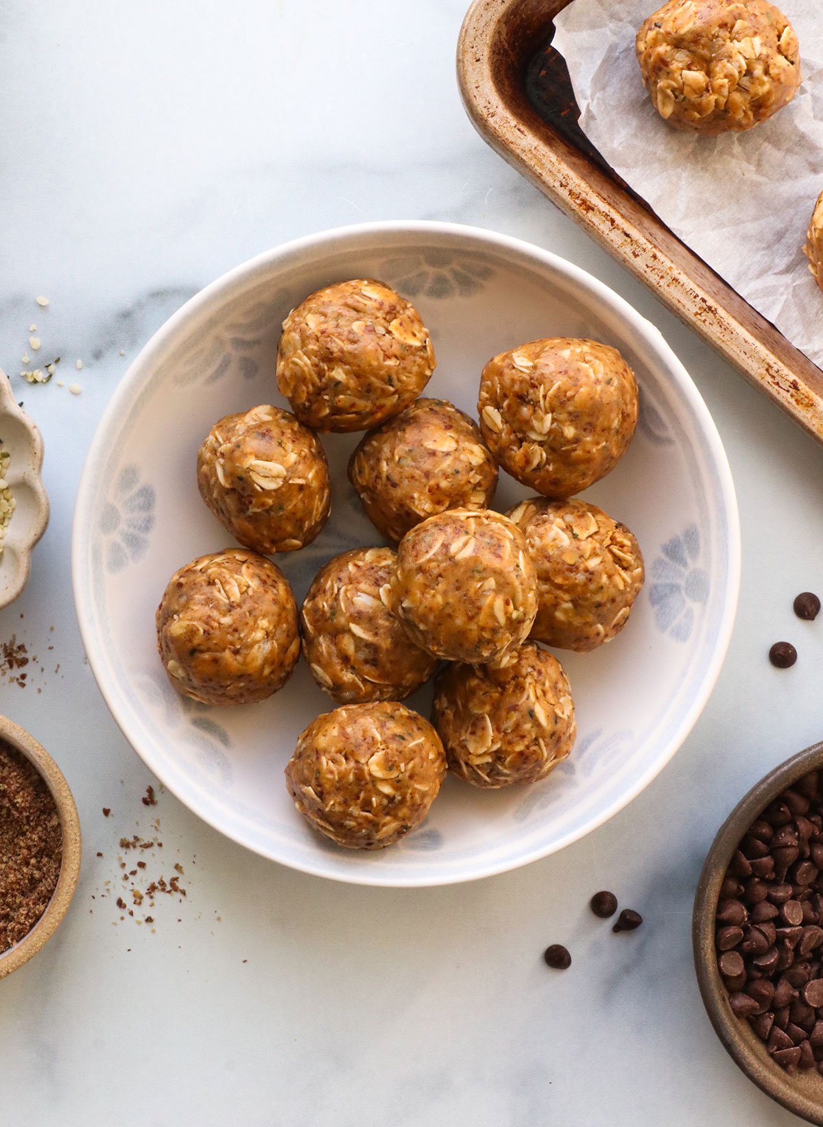 peanut butter protein balls in a white bowl with seeds on the side.