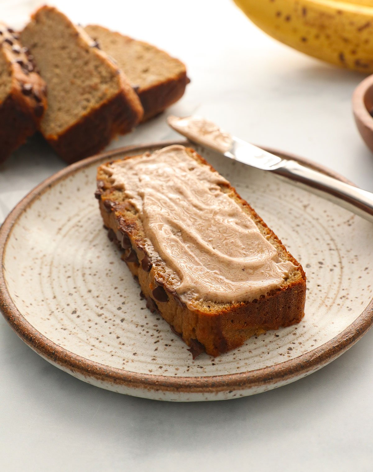 almond butter spread on a slice of protein bread on a plate.