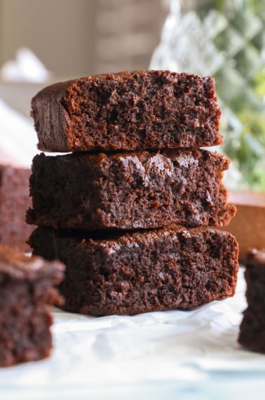 protein brownies stacked on white parchment paper.