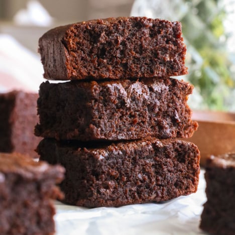 protein brownies stacked on white parchment paper.