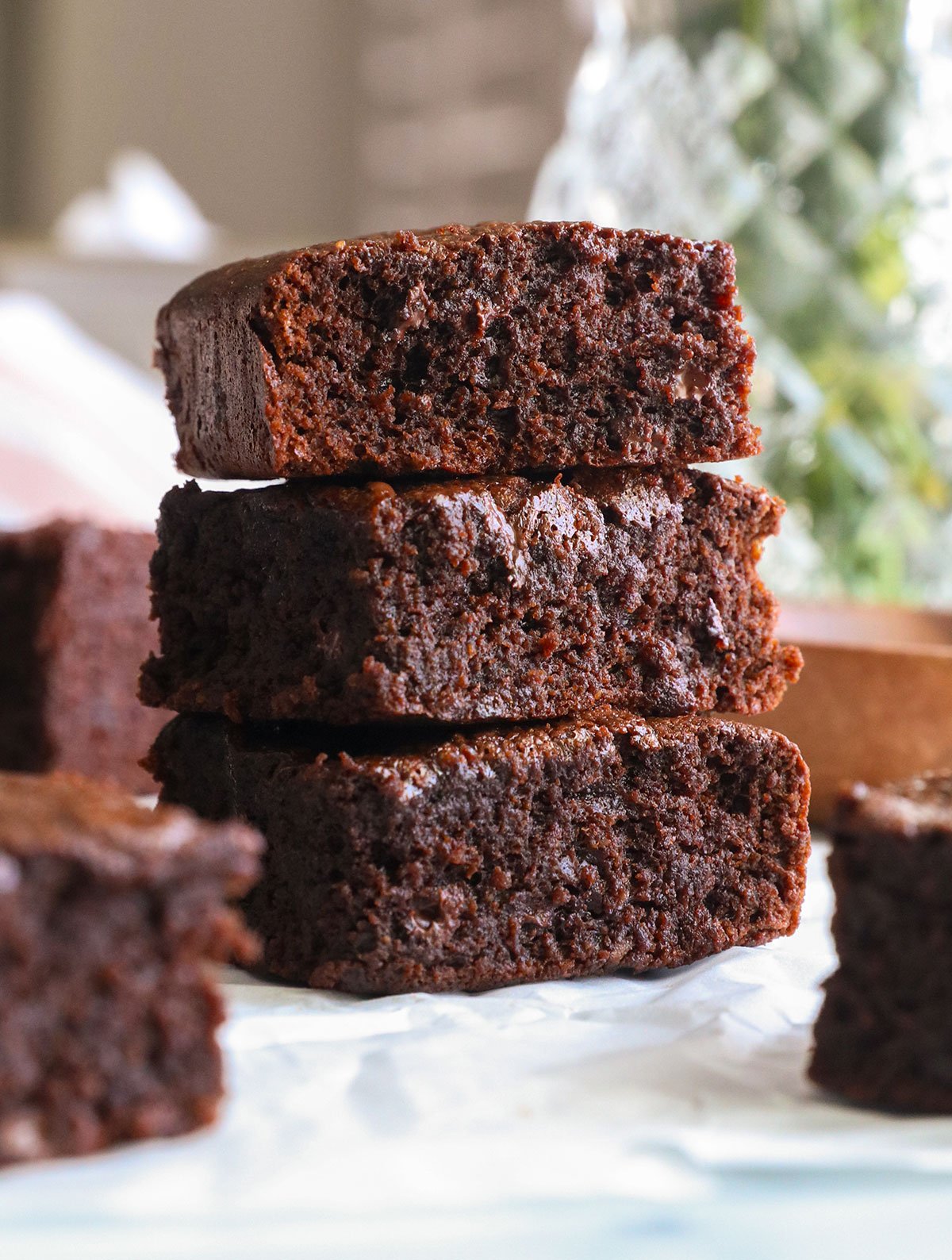 protein brownies stacked on white parchment paper.