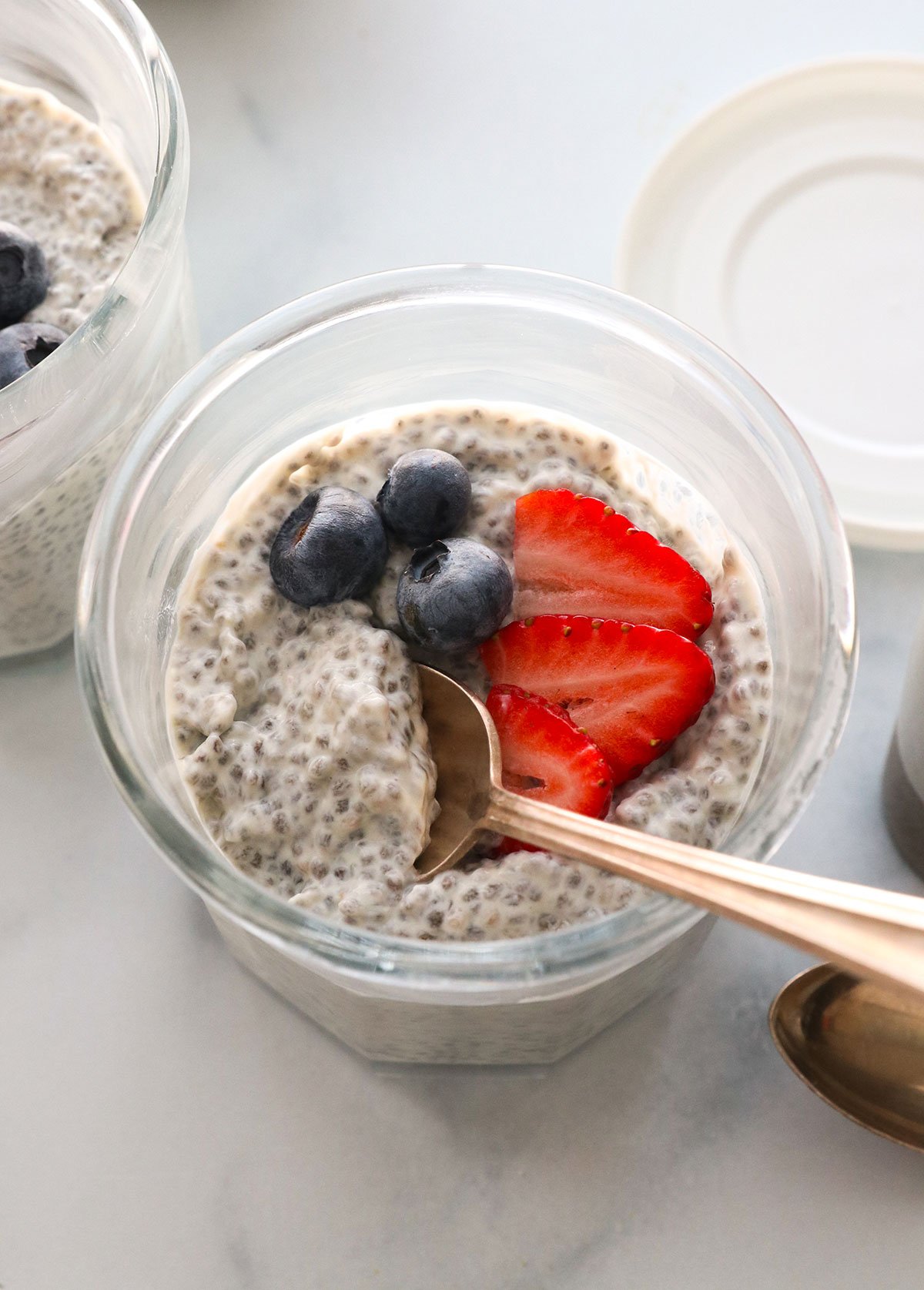 protein chia pudding in a glass jar topped with fresh berries. 