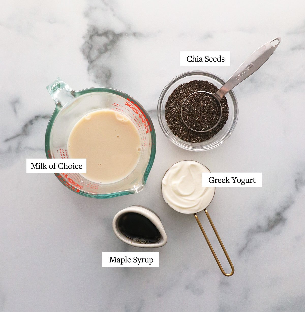 chia seeds, milk, yogurt, and maple syrup labeled on a white surface.