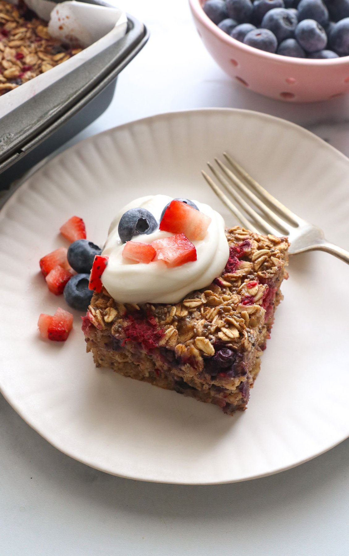 slice of berry baked oatmeal topped with greek yogurt and berries.