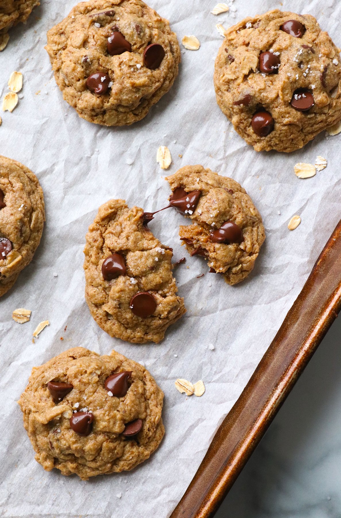 gluten-free oatmeal cookie split in half on a lined baking sheet.