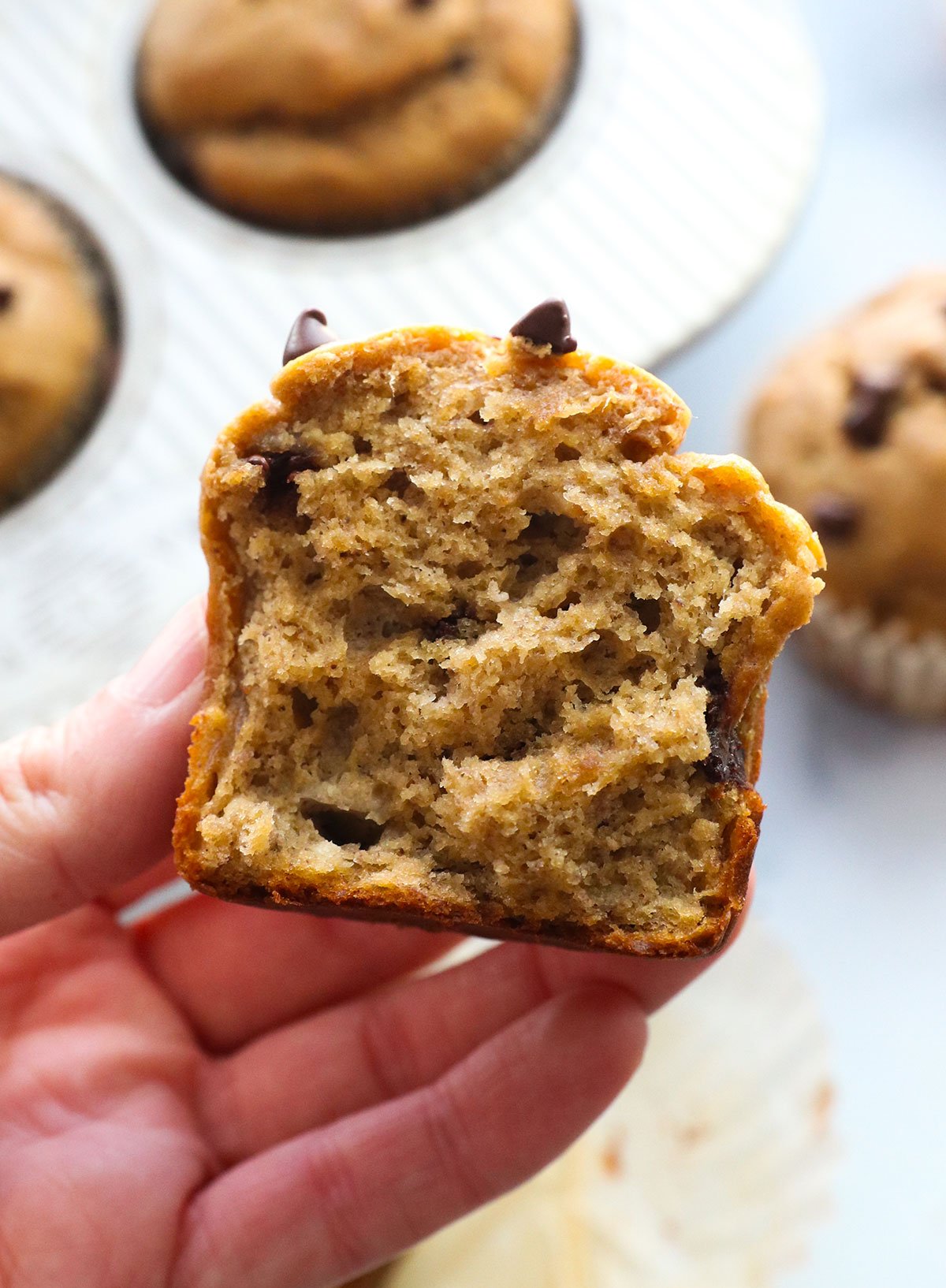 hand holding half of a protein muffin to show the fluffy texture.