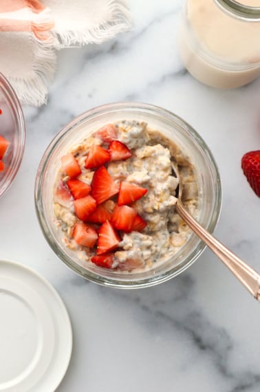 strawberry overnight oats overhead in a glass jar with a spoon.