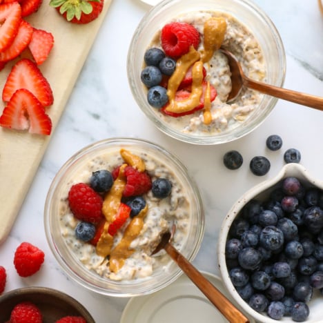 two jars of protein overnight oats topped with fruit and nut butter.