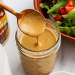 honey balsamic dressing poured off of a spoon into a jar.