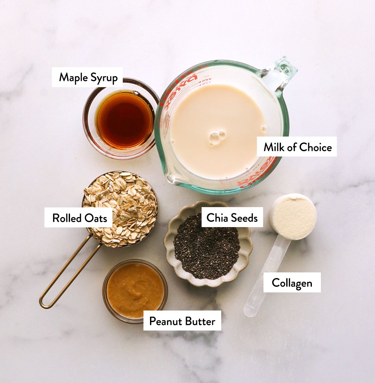 Milk, oats, chia seeds, collagen and peanut butter mark on a white surface.