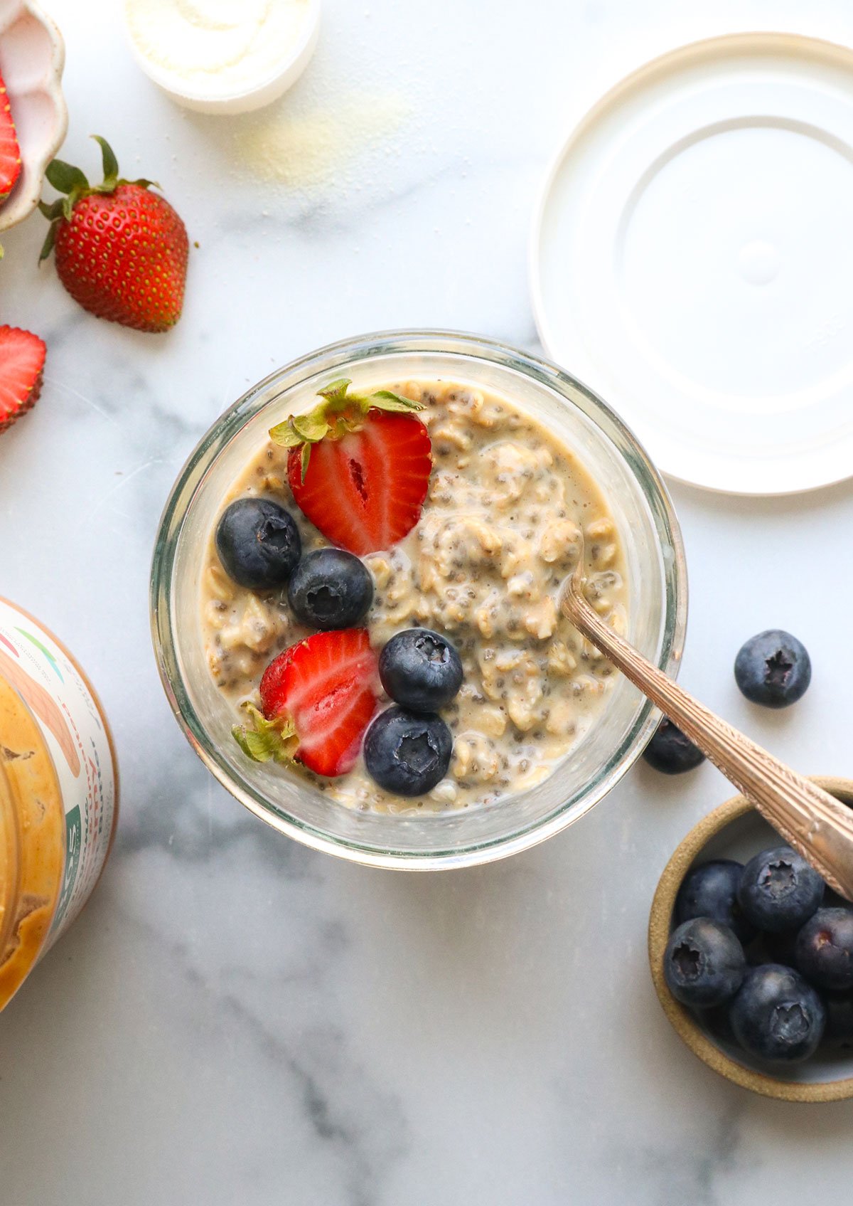 Protein overnight oats in glass jars with lids and berries nearby.