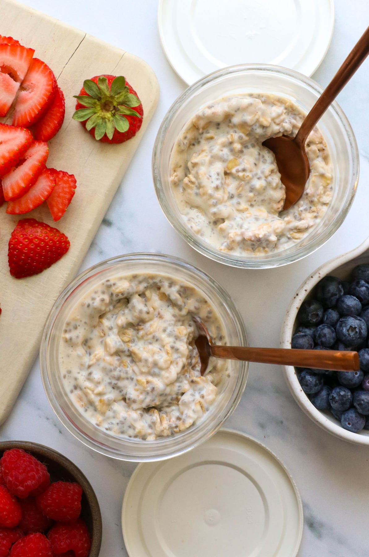thickened protein oats in two glass jars near fresh berries. 