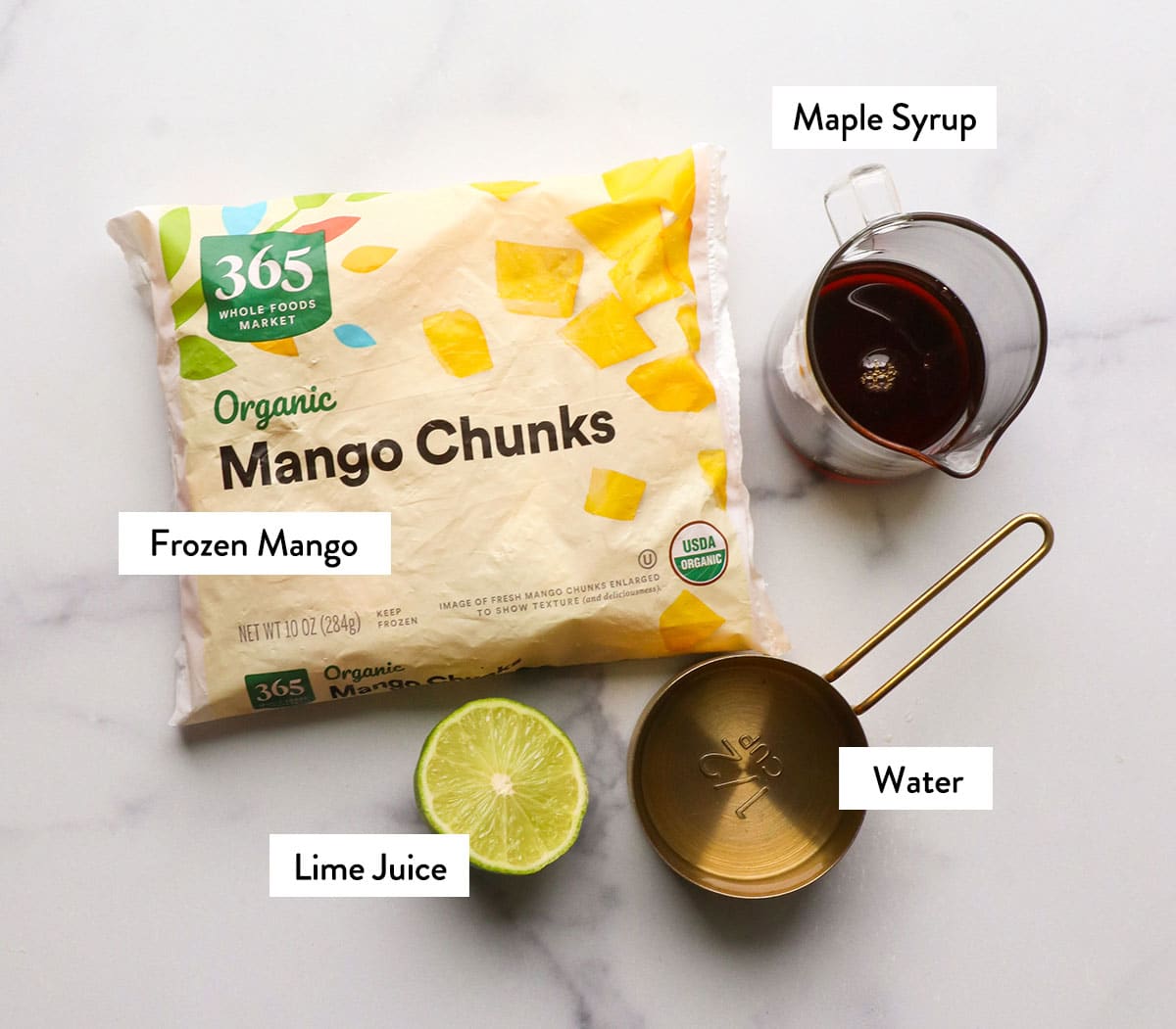 frozen mango, maple syrup, and lime labeled on a white surface.