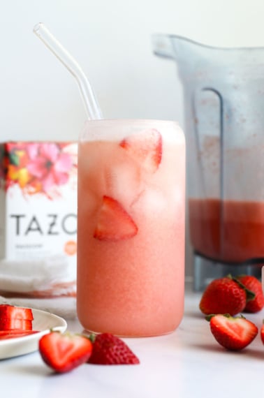 homemade pink drink in a glass with fresh strawberries.