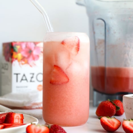 homemade pink drink in a glass with fresh strawberries.