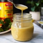 apple cider vinegar dressing dripping off of a spoon into the jar.