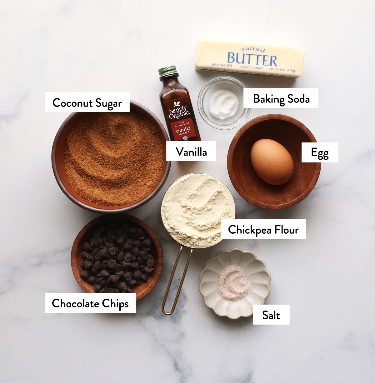 chickpea flour, coconut sugar, egg, chocolate chips, and butter labeled on a white surface.