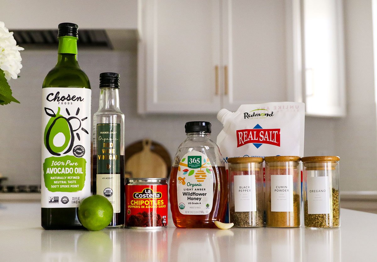 Bottle of oil, vinegar, honey and spices sitting on the white counter.