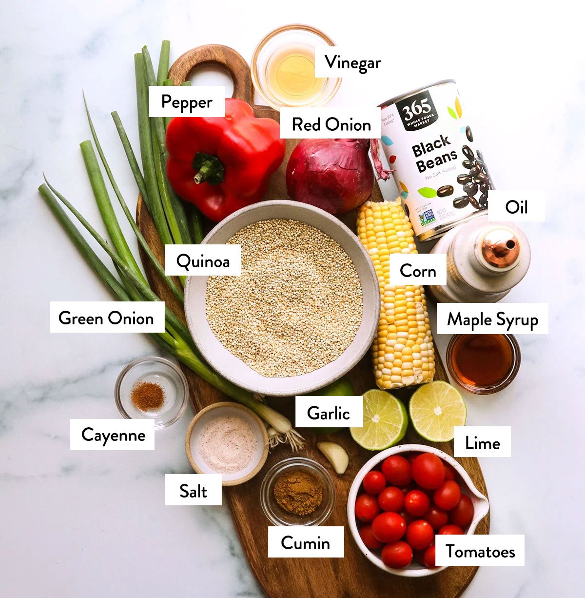 quinoa, black beans, vegetables, and seasonings labeled in bowls. 