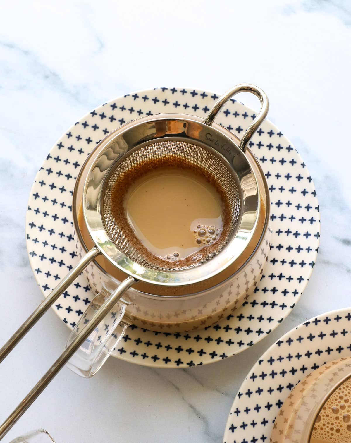 small strainer sitting on top of a serving mug for chai latte.