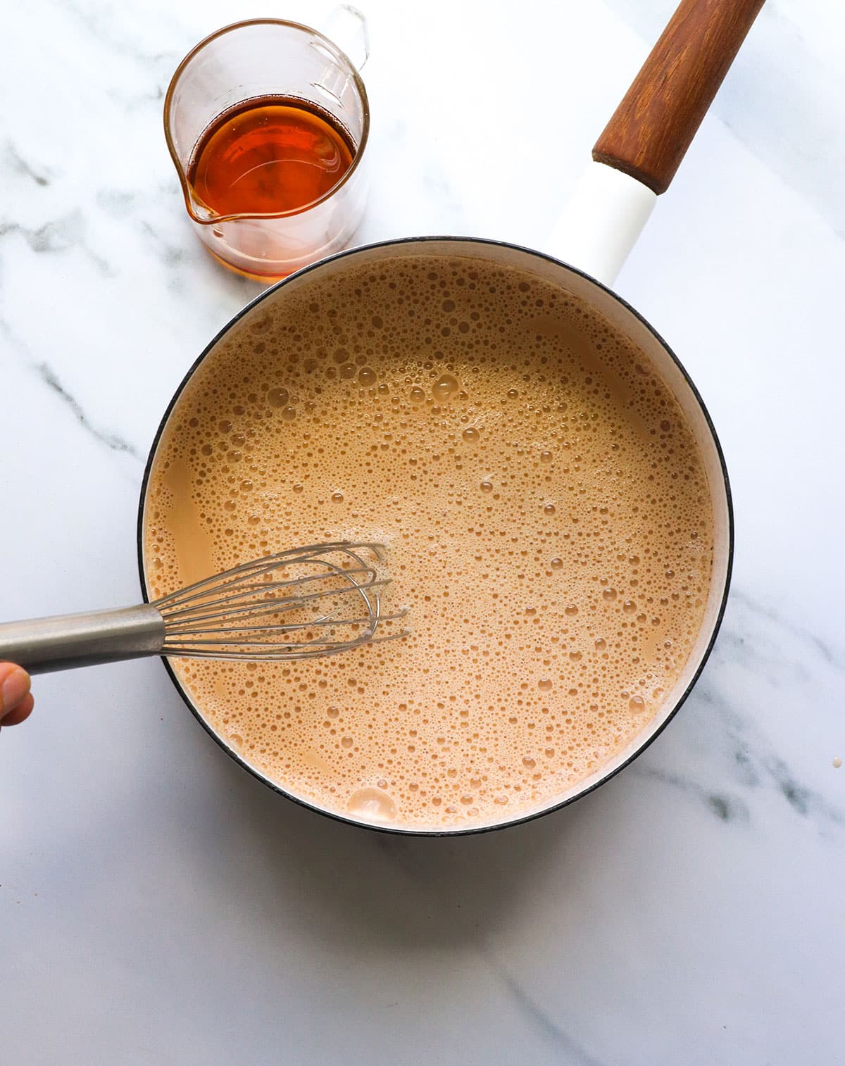 whisk stirring chai latte in a saucepan.