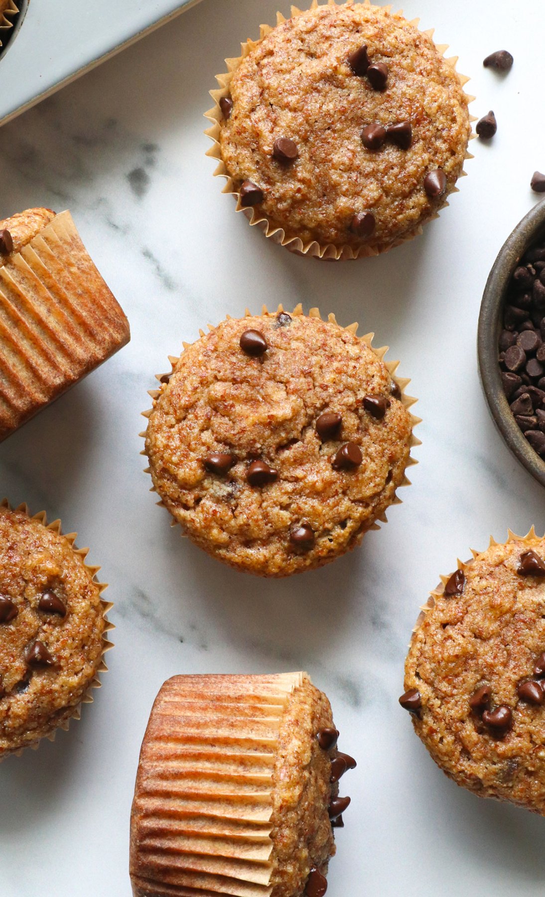 several almond meal muffins cooled on a marble surface.
