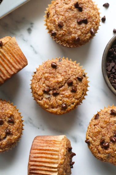 several almond meal muffins cooled on a marble surface.