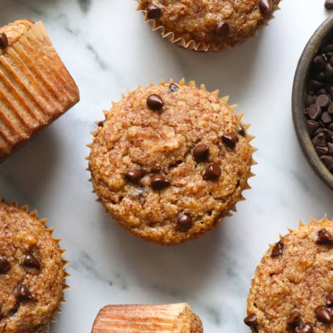 several almond meal muffins cooled on a marble surface.
