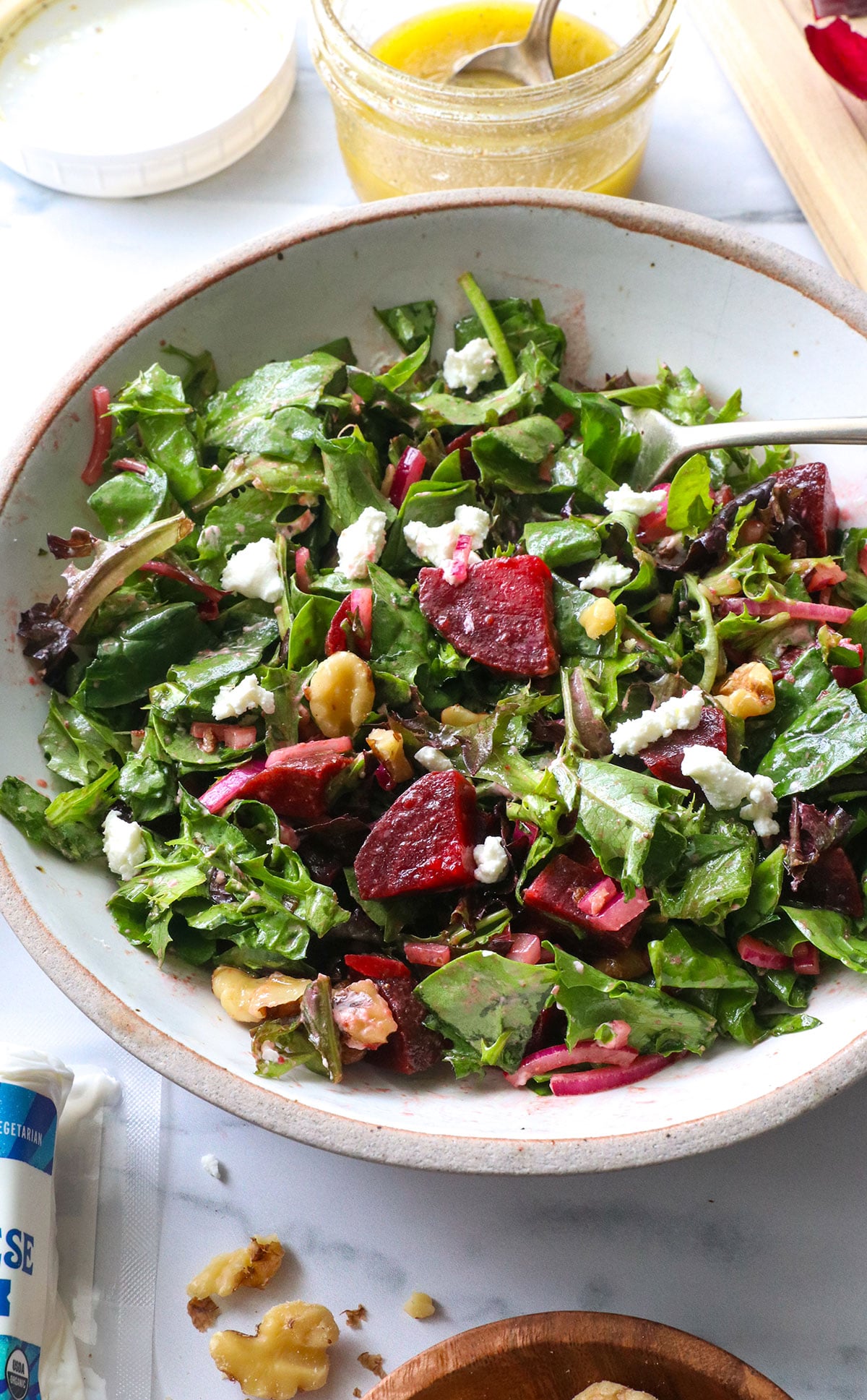 beet salad from an angle with steamed beets, walnuts, and goat cheese on top.