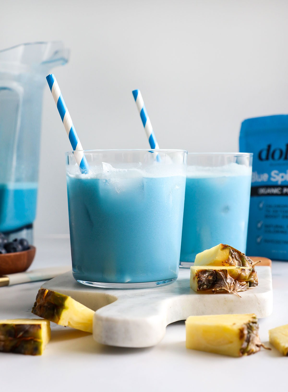 blue milk served in two glasses with blue striped straws.