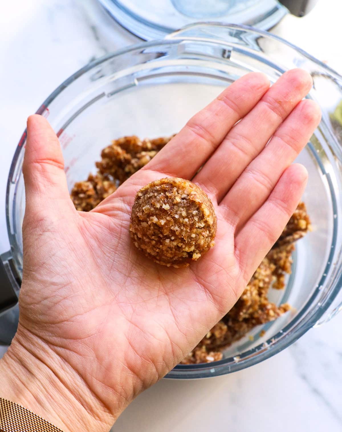 A scoop of date ball mixture in a hand before rolling.