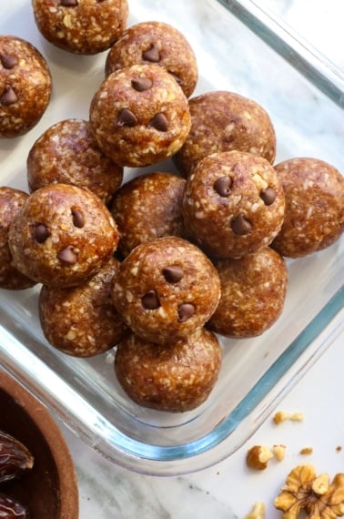 date energy balls with mini chocolate chips stored in a glass container.