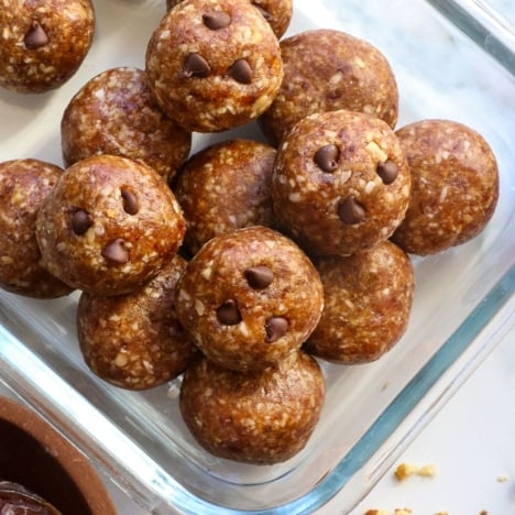 date energy balls with mini chocolate chips stored in a glass container.