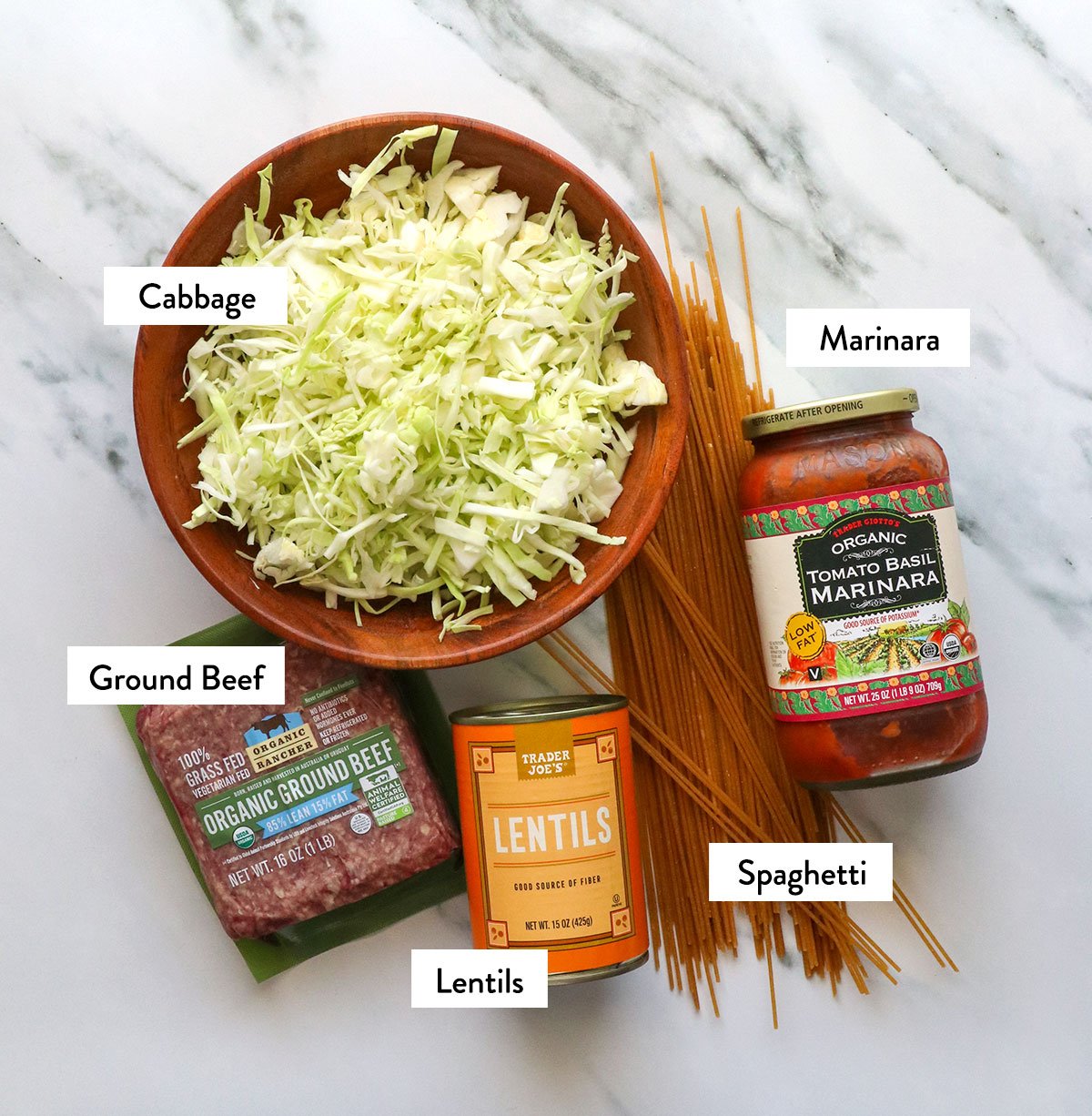 shredded cabbage, beef, noodles, and marinara labeled on a surface.