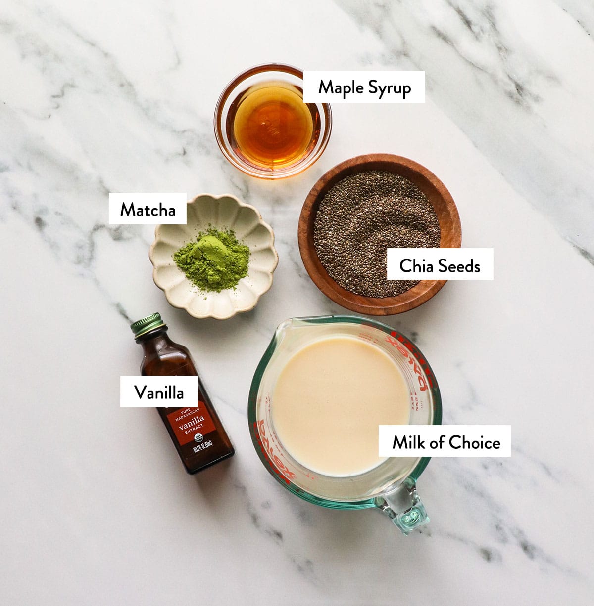 milk, chia seeds, matcha, and maple syrup labeled on a white surface.