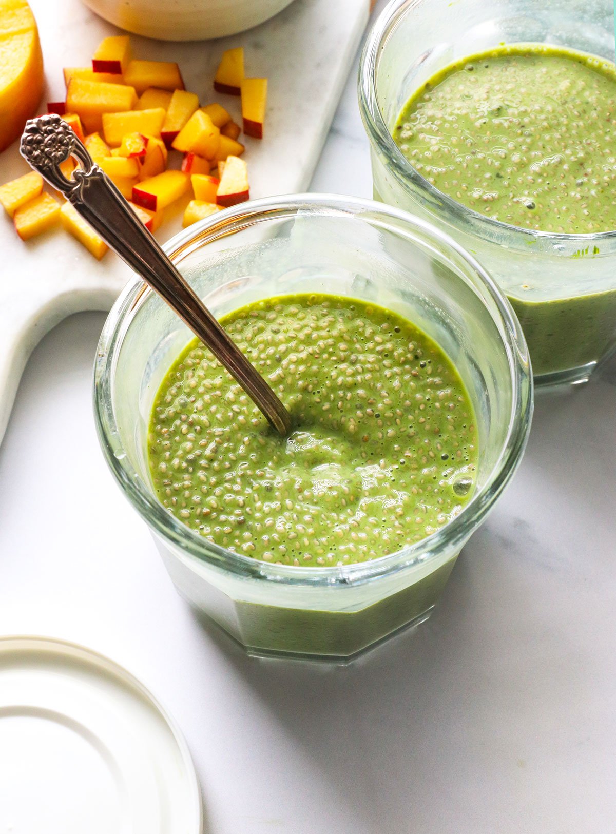matcha chia pudding thickened in two jars with a spoon.