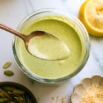 pumpkin seed pesto in a jar and lifted on a spoon.