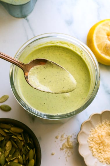 pumpkin seed pesto in a jar and lifted on a spoon.