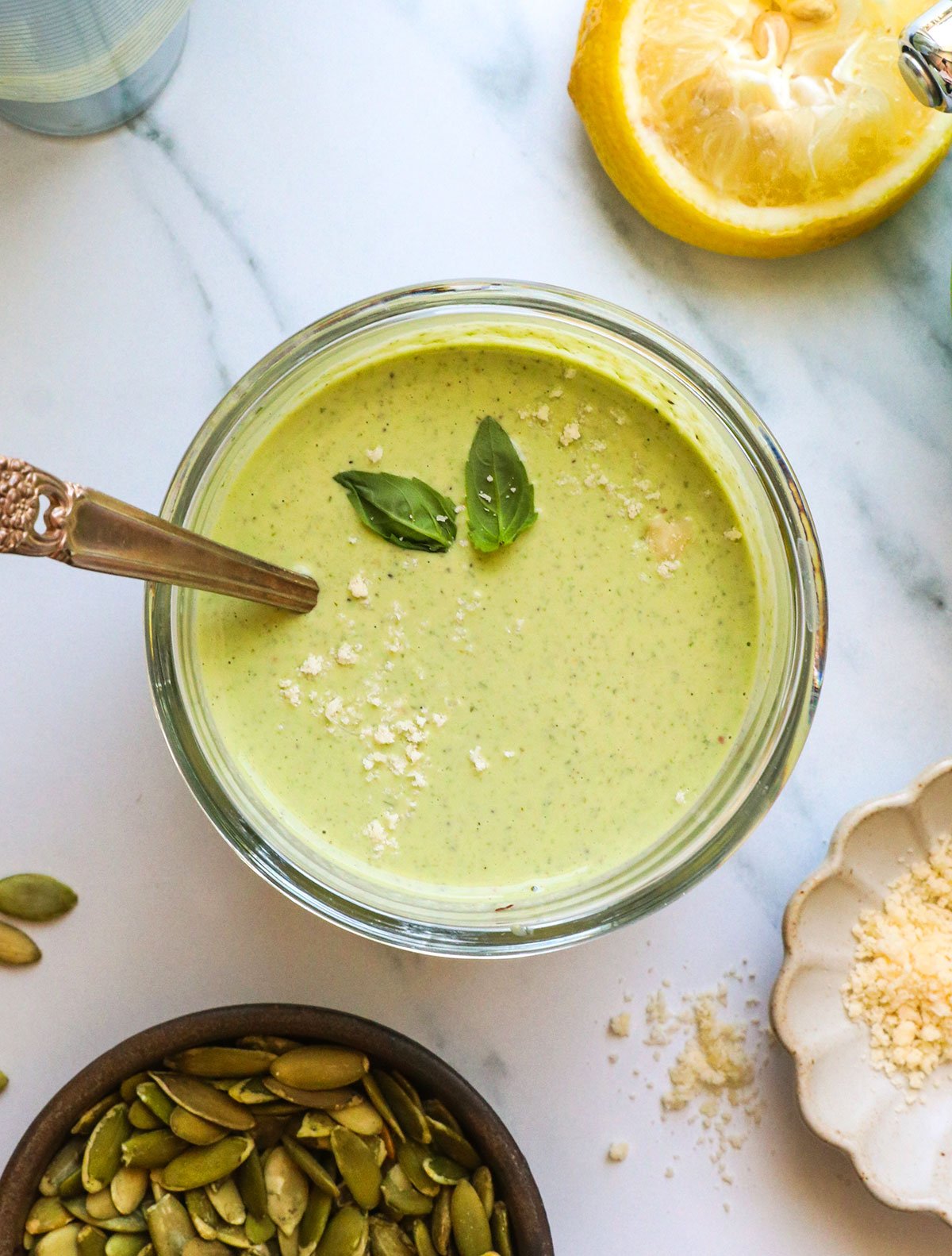 pumpkin seed pesto in a jar topped with fresh basil leaves. 